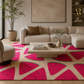 A modern living room featuring a beige sectional sofa, a low wooden coffee table, and a large area rug with a bold pink watermelon slice pattern on a cream background.