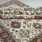 Stack of patterned rugs with intricate designs on a neutral background
