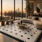 A modern curved cream sofa and matching accent chair in a luxury high-rise living room with a city skyline view at sunset, styled on a black and cream patterned area rug.