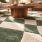Wooden coffee table on a checkered green and beige rug in a living room.
