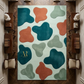 Colorful abstract-patterned rug on a wooden floor with a visible brand logo.