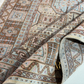 Close-up of a patterned rug with intricate designs and a brand logo.