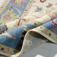 Close-up of a colorful patterned rug with blue, pink, and beige colors.