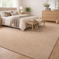 Beige bedroom with a large rug, bed, and dresser.