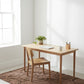 Wooden desk with chair in a bright room with a brown textured rug.