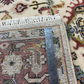 Rug with a ruler for scale showing intricate patterns and colors.