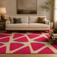 A beige area rug with a bold watermelon slice pattern in bright pink and green, styled in a modern living room setting under a cream sofa.