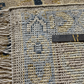 Close-up of a patterned rug with a brand tag, showing texture and color details.