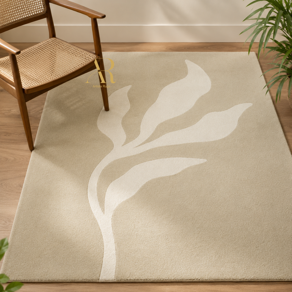 A beige area rug with a large white leaf motif, styled in a room setting with a wooden armchair and a potted plant.