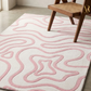 Pink and white patterned rug with a wooden chair on a light wood floor.