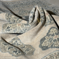 Textured fabric with intricate patterns in shades of gray and beige.