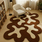 Modern living room with a wavy brown and white rug, white armchair, and bookshelf.