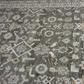 Close-up of a patterned rug with geometric designs in gray, beige, and white.