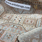 Close-up of a patterned rug with 'www.artistarugs.com' label.