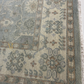 Close-up of a patterned rug with intricate designs in shades of gray, brown, and beige.
