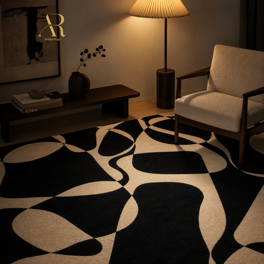 A modern abstract area rug with a bold black and cream wavy pattern, styled in a warm, dimly lit living room next to a beige armchair and a lit floor lamp.