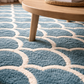 Close-up of a blue and white geometric patterned rug with a wooden coffee table.