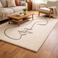 Living room with a rug featuring a black abstract design, wooden coffee table, and beige sofa.