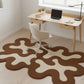 Modern office with a wavy brown and beige rug, desk, chair, and laptop.