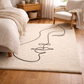 Beige rug with black abstract design in a bedroom setting