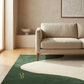 Beige sofa in a room with a green rug and abstract art on the wall.
