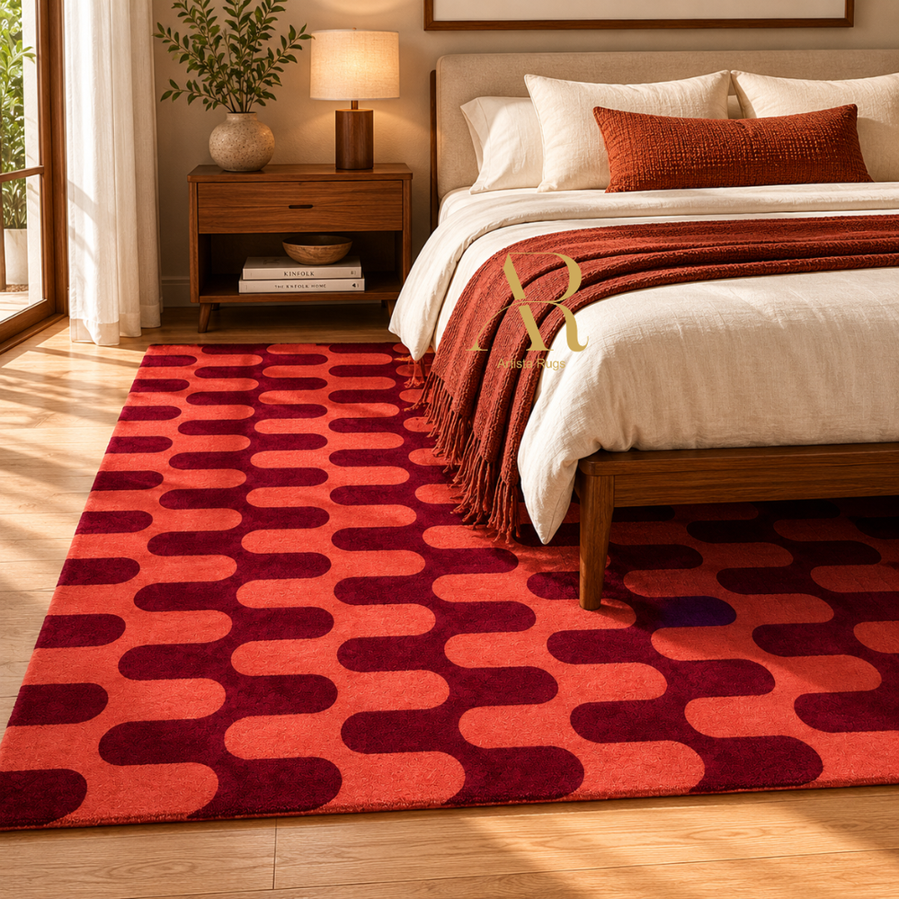 A large area rug with a bold geometric pattern of red and burgundy rounded ovals, styled in a warm, modern bedroom next to a wooden bed.