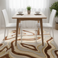 Dining room with wooden table, white chairs, and decorative rug.