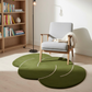 Green leaf-shaped rug on a wooden floor with a bookshelf and chair in the background.