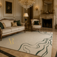 A large cream-colored area rug with a dark green abstract wavy pattern, styled in a luxurious, elegant living room with a matching beige sofa, armchair, and ornate fireplace.