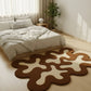 Modern bedroom with a unique brown and white rug on a wooden floor.