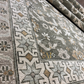 Close-up of a patterned rug with geometric designs in shades of brown, beige, and gray.