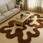 Living room with a unique brown and white rug, beige sofa, and wooden coffee table.