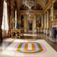 Opulent room with a colorful rug, grand chandeliers, and classical decor.