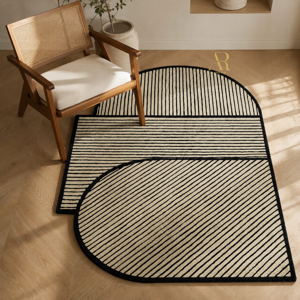 Three interlocking modern rugs with a black and beige striped pattern, styled on a light wood floor next to a wooden armchair.
