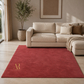 Beige sectional sofa in a living room with a red rug featuring a gold logo.