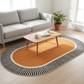 Living room with a gray sofa, wooden coffee table, and a round orange rug with black stripes.