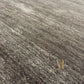 A close-up view of a dark gray textured surface with fine granular material and a small gold stylized logo near the lower right.
