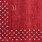 A close-up of a red textured fabric with a fine vertical ribbed pattern, decorated with small white floral motifs along the left and bottom edges, and a gold 'AR' monogram logo near the top center.