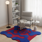 Modern living room with a gray armchair, colorful rug, and bookshelf.