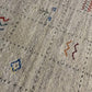 Close-up of a textured light beige rug with a Southwestern pattern of small black dots and colorful embroidered accents in blue, red, orange, and green.