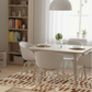 Dining room with a table and chairs, bookshelf, and rug.