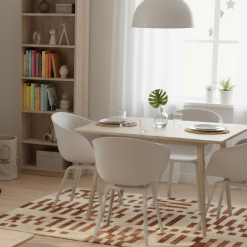 Dining room with a table and chairs, bookshelf, and rug.