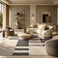 A luxury modern living room featuring a large geometric area rug in beige, gray, and white, styled with a curved cream sofa, matching armchairs, a stone coffee table, and elegant gold shelving.