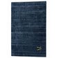 A dark navy blue area rug with a subtle horizontal textured pattern and a small gold monogram logo in the bottom right corner, shown against a plain white background.