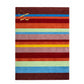 A rectangular area rug with vertical stripes in multiple colors including brown, blue, red, orange, pink, yellow, green, and light blue, featuring a gold embroidered monogram logo in the bottom left corner.