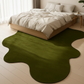 Green abstract rug on a light wooden floor in a bedroom setting.