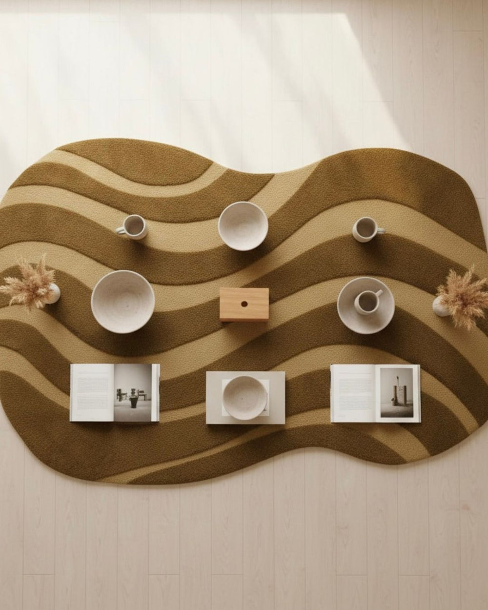 Wavy brown rug with white cups, a wooden box, and small decorative items on a light background