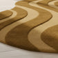 Brown and beige wavy patterned rug on a light wooden floor.