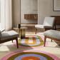 Modern living room with a colorful geometric rug, gray chairs, and wooden furniture.