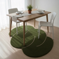 Dining table with chairs and a green rug on a wooden floor.